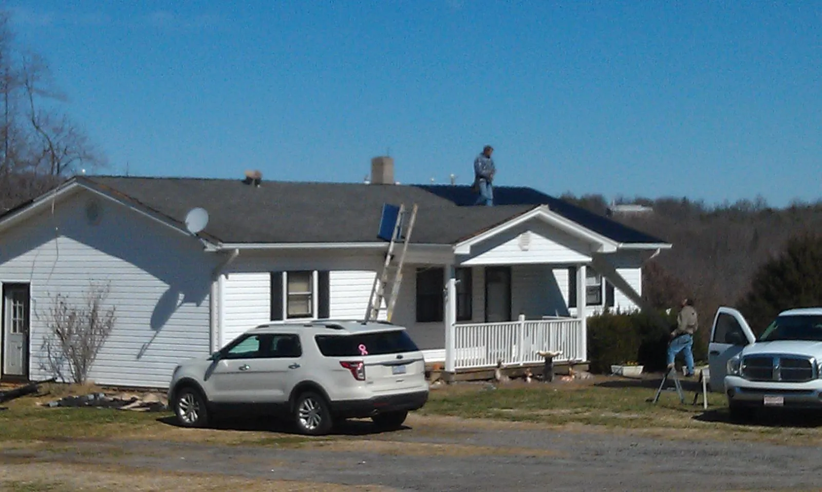 Roofers stripping shingles from a white ranch house roof in Herndon